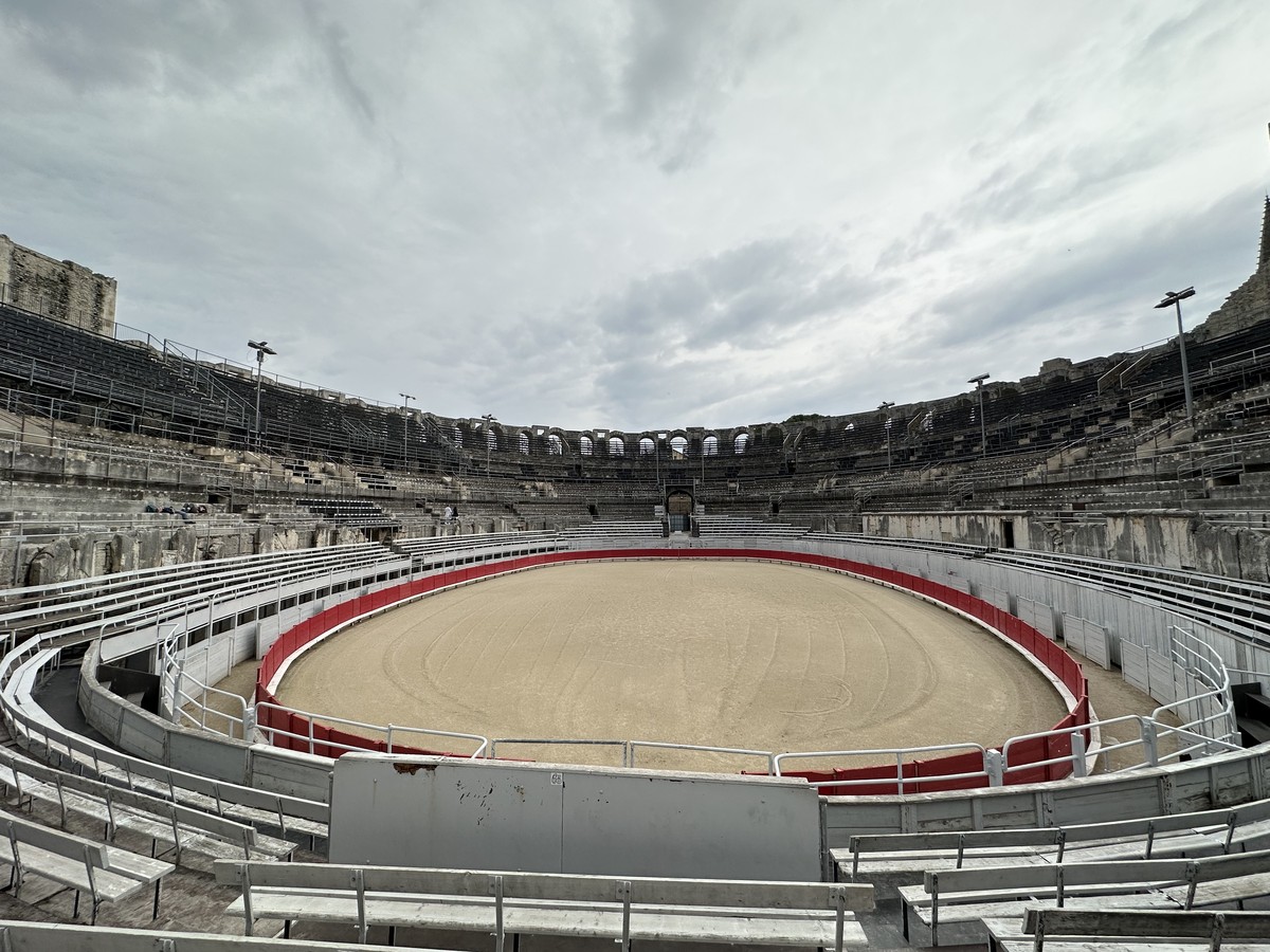 Inside the Arles Amphitheater arena with stone seating tiers