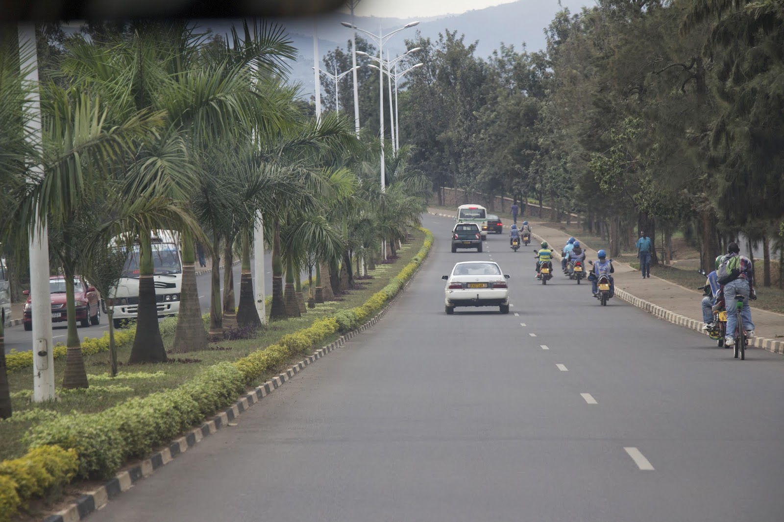 Tree-lined road in Kigali with cars and motorcycles