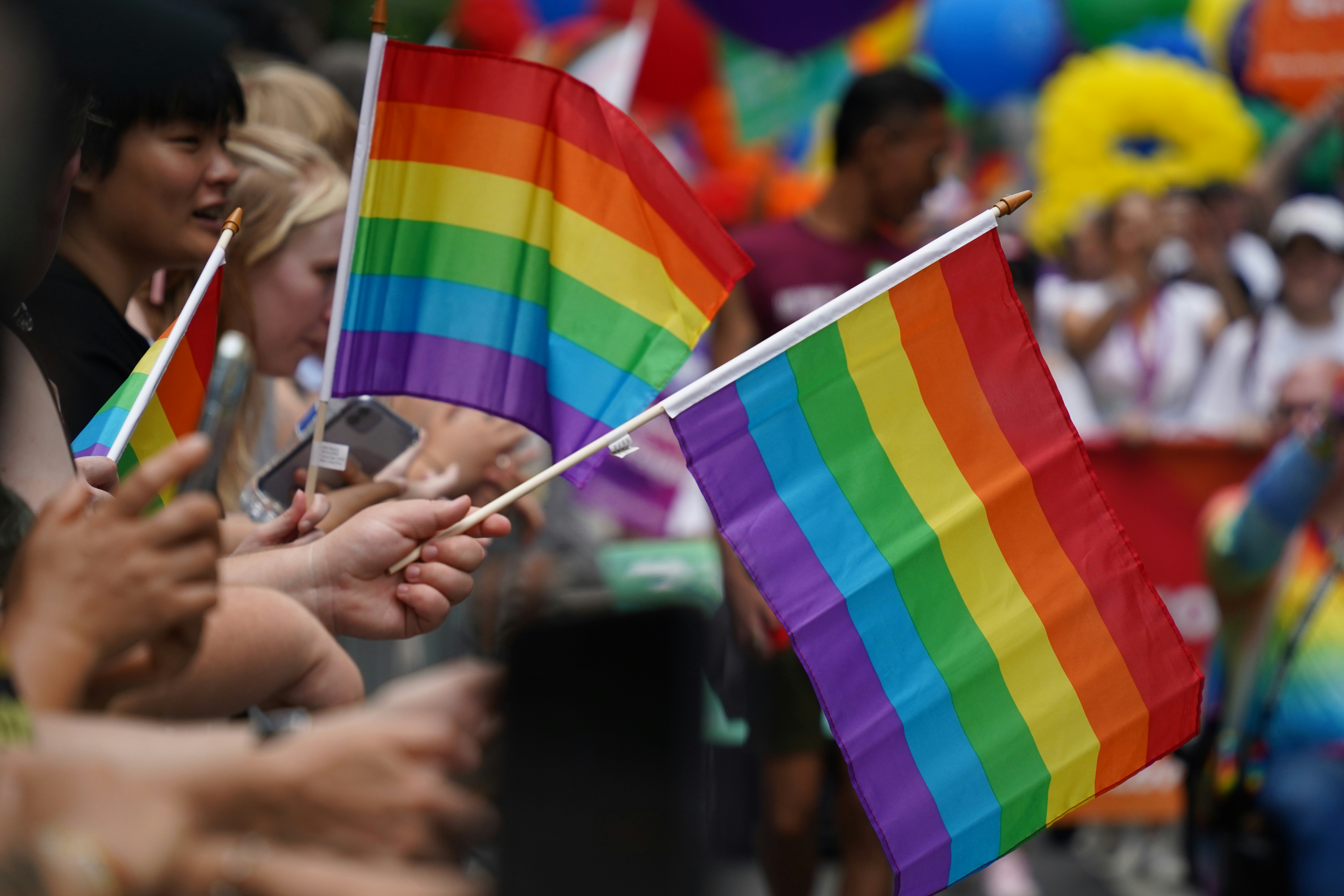 Group of LGBTQ+ people holding a rainbow flag together
